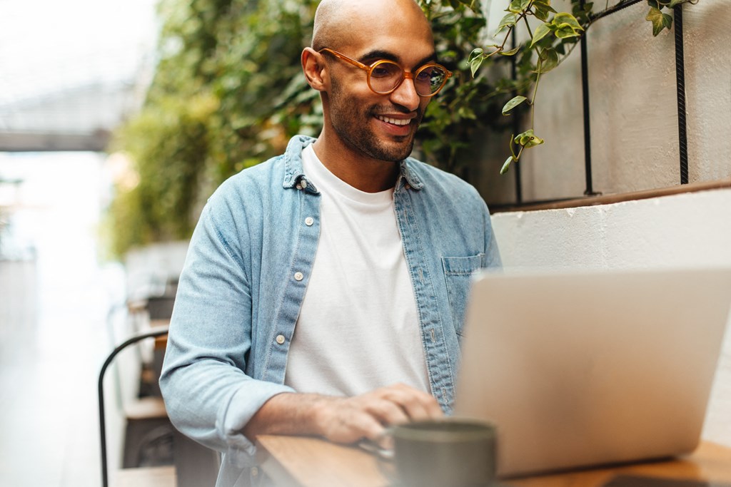 a man sitting at a table using a laptop computer