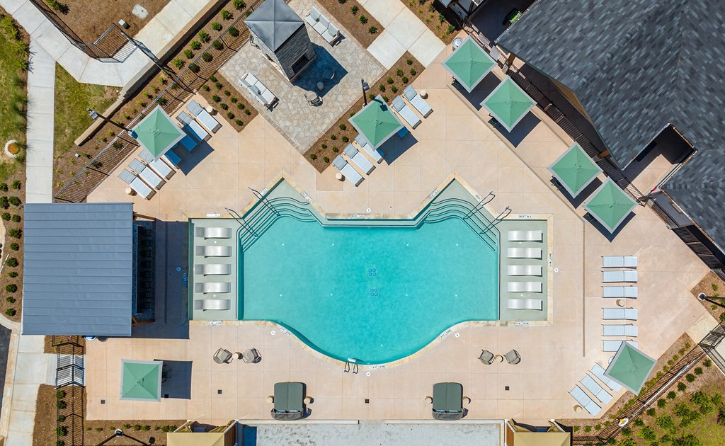 an overhead view of a swimming pool with blue water and umbrellas
