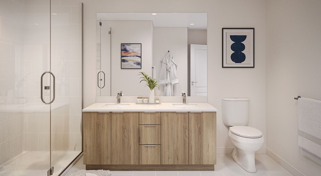 A modern bathroom with a glass shower door, a white toilet, and a wooden vanity with two sinks.