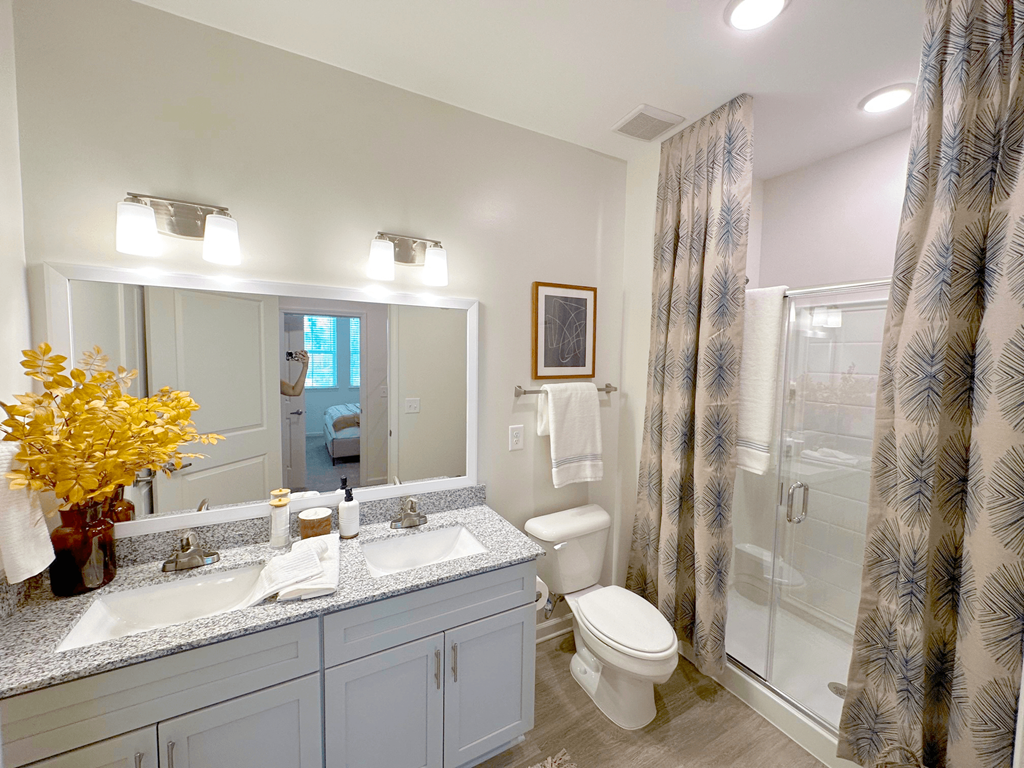 A bathroom with a white sink, toilet, and a mirror.