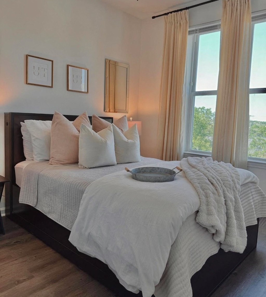 A bed with white pillows and a white blanket with a grey tray on it.