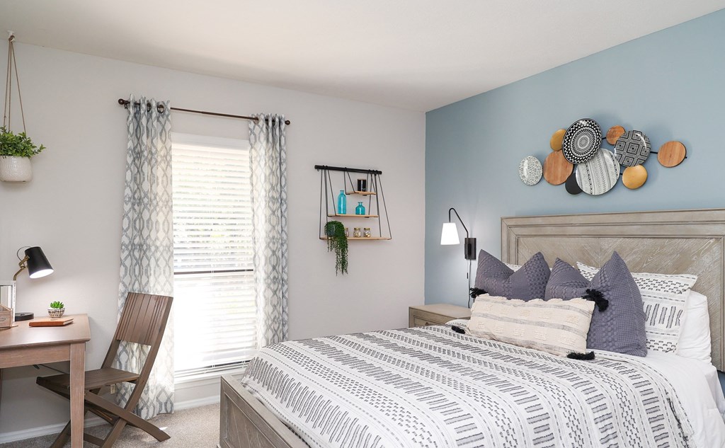 a bedroom with a bed and a desk with a window