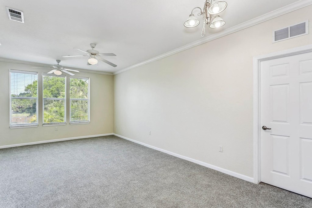 an empty living room with a white door and a ceiling fan