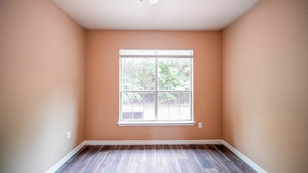 an empty room with a large window and wooden floors