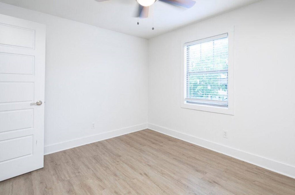 an empty room with a window and a ceiling fan