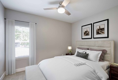 A bedroom with a large bed and two pictures on the wall.