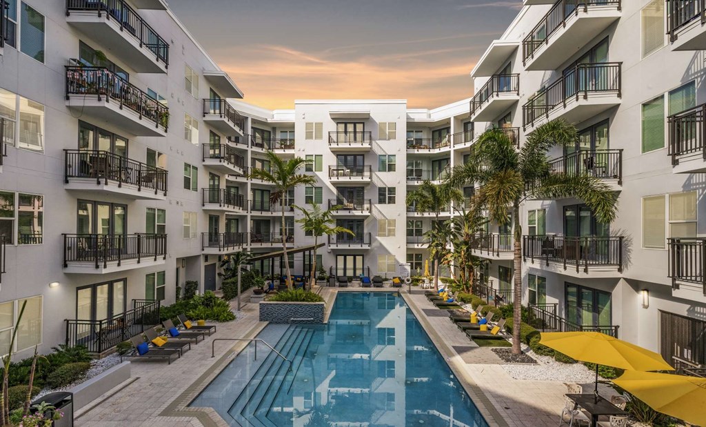 A swimming pool is surrounded by apartment buildings.