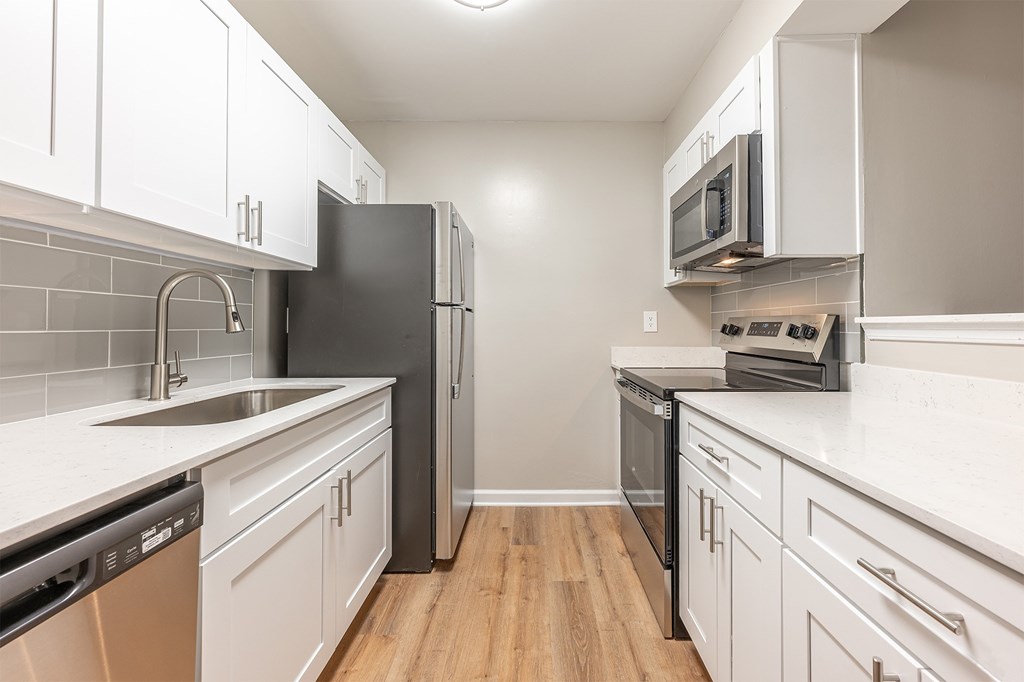 A kitchen with white cabinets and a black refrigerator.