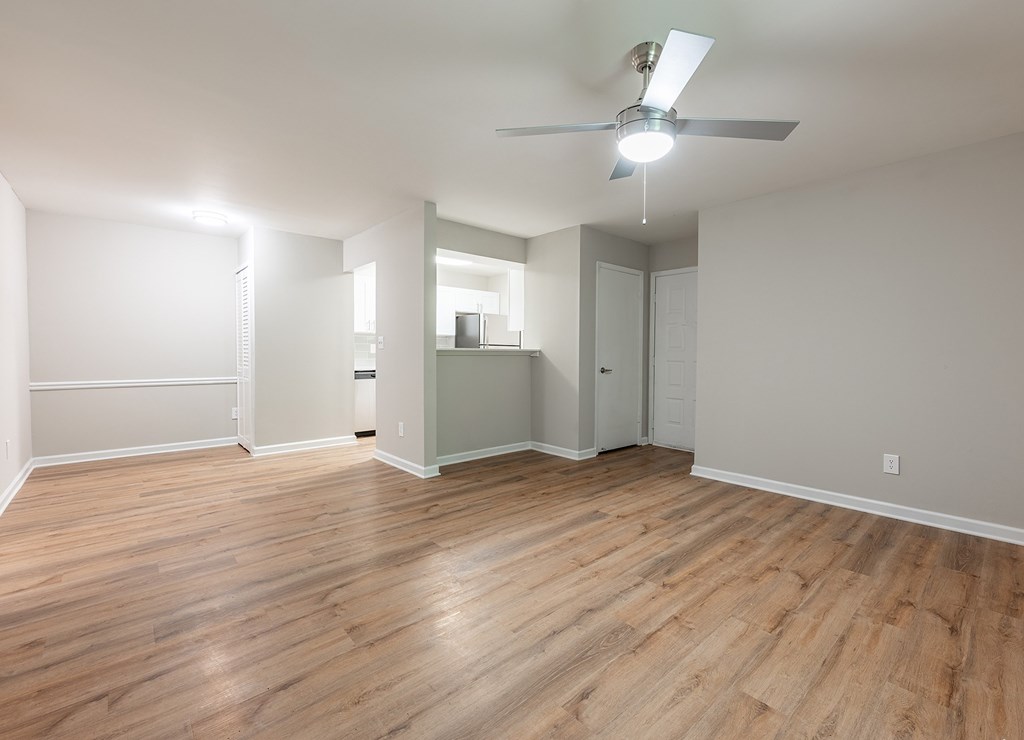 A room with a ceiling fan and wooden flooring.
