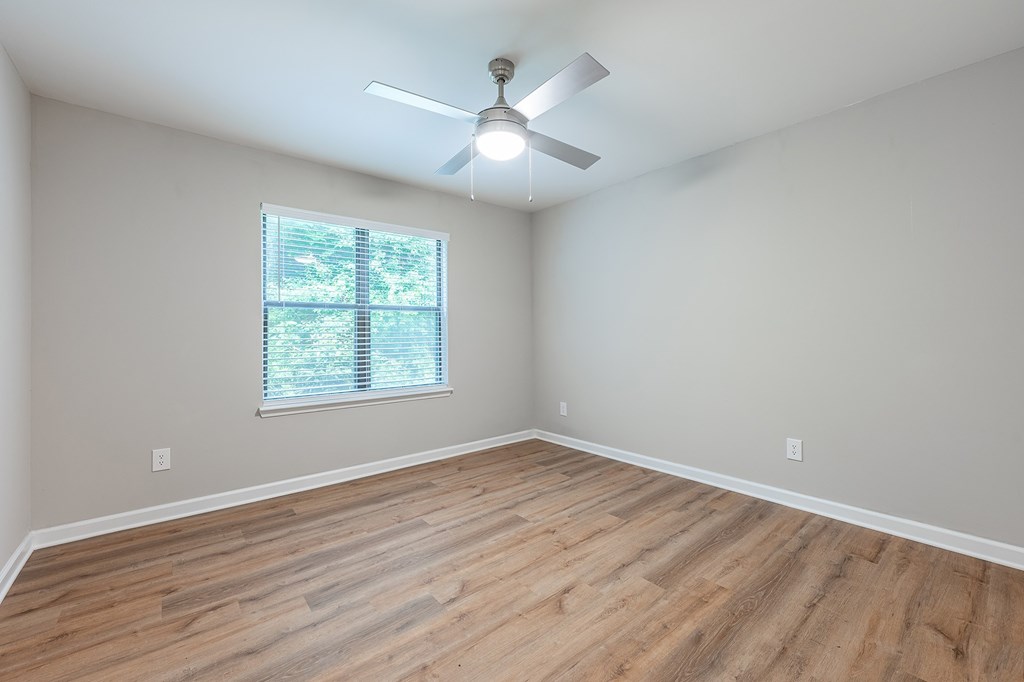A room with a ceiling fan and a window with blinds.