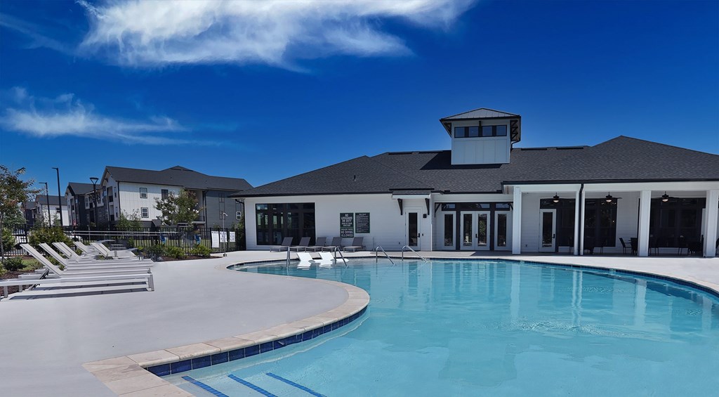 Downtown Greenville SC Apartments - The Aster - Pool with Lounge Chairs and Clubhouse in the Background.