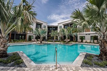 a swimming pool with palm trees and apartments in the background
