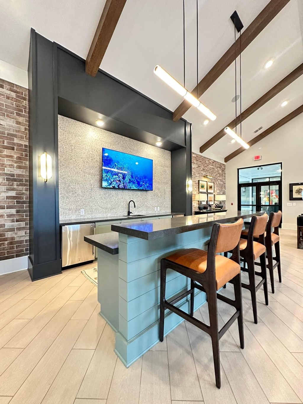 a kitchen with a bar with chairs and a tv