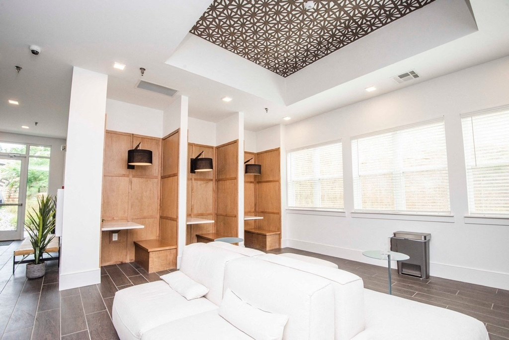 A white couch is in the middle of a room with a wooden wall and a ceiling with a pattern.