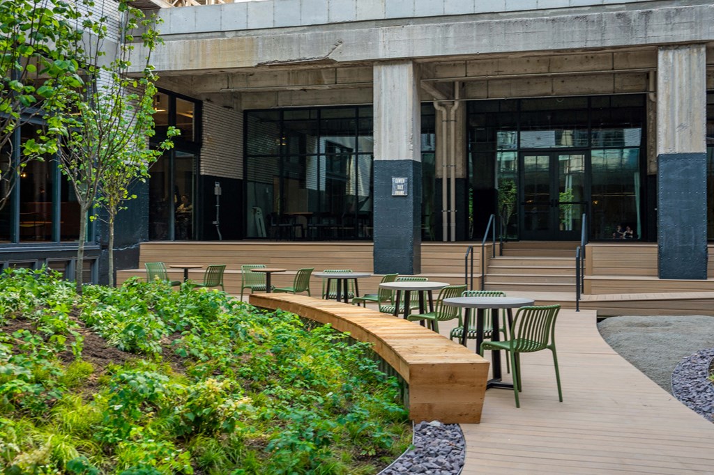 tables and chairs on a wooden deck in front of a building