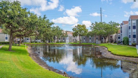 a pond with a fountain in the middle of an apartment complex