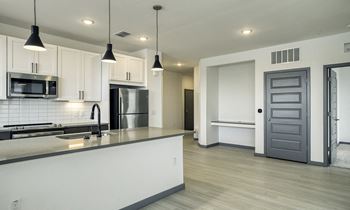 an open kitchen and living room with white cabinets and stainless steel appliances