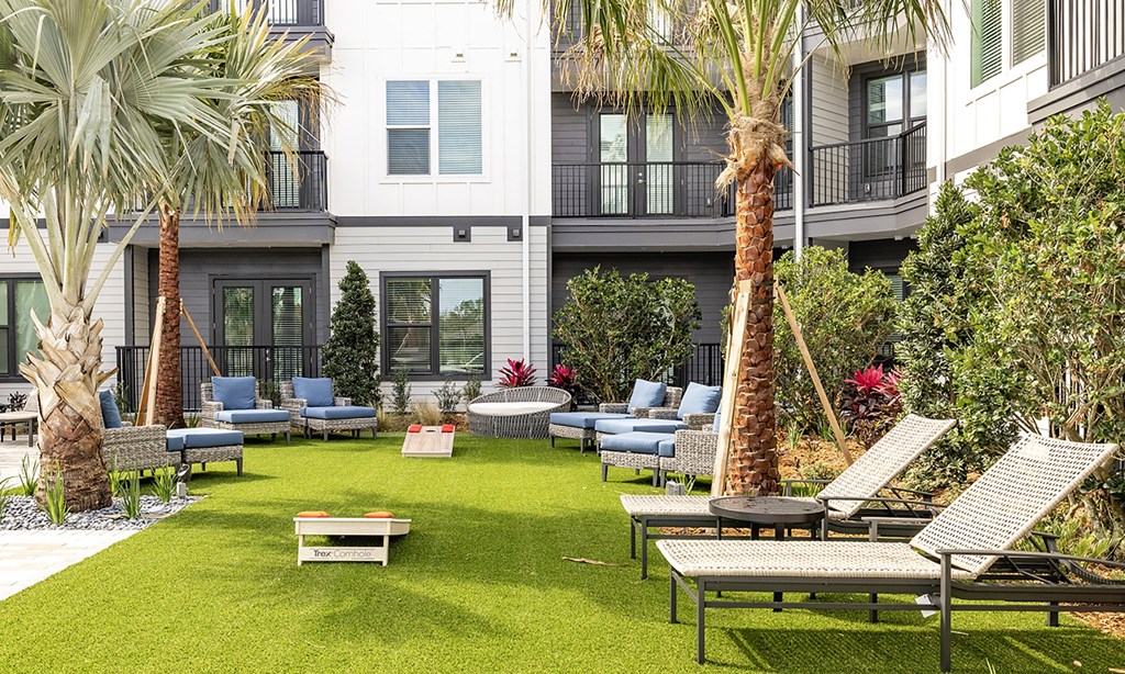 a courtyard with lounge chairs and tables and palm trees in apollo beach, florida