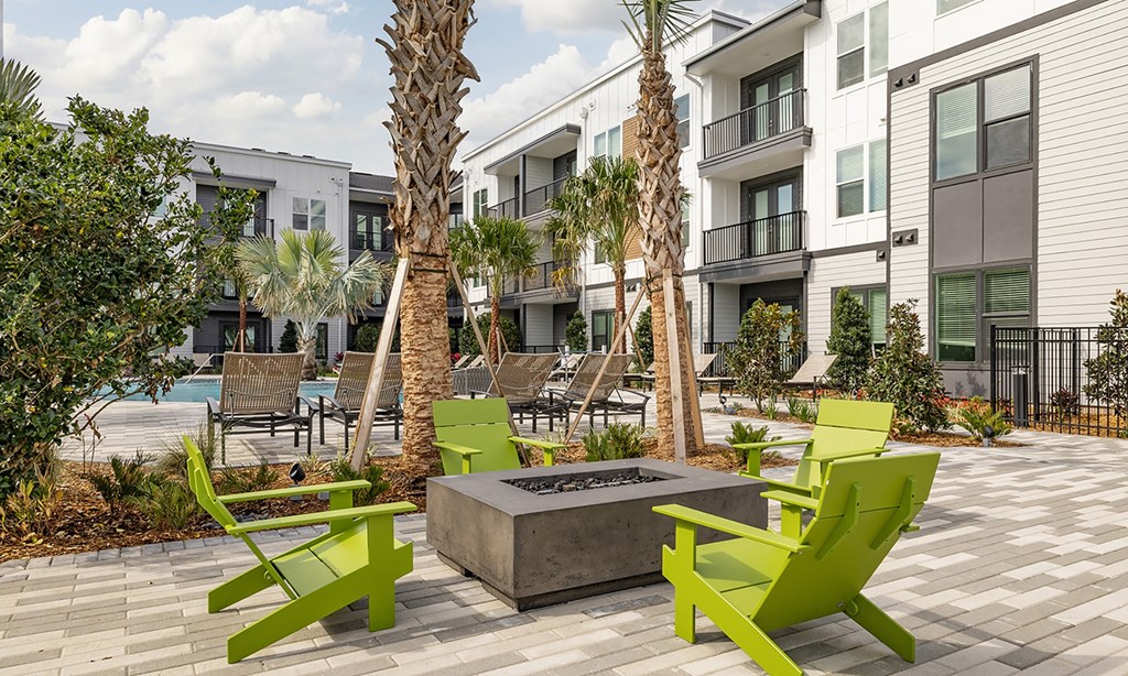 an apartment courtyard with green chairs and a fire pit in apollo beach, florida