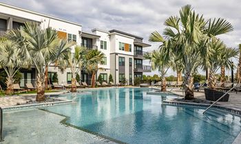 a swimming pool with palm trees in front of apartment buildings