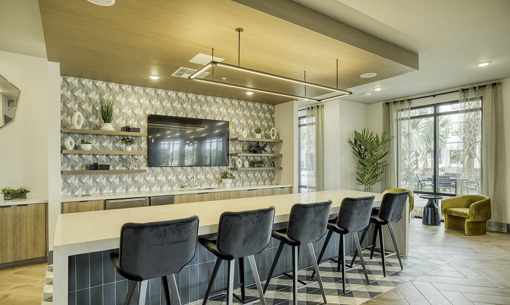 a long bar with stools in a room with chairs and a television