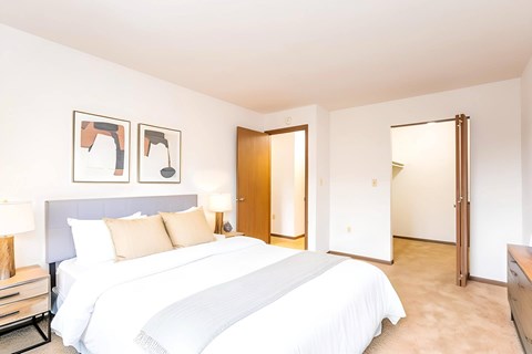 A bedroom with a large bed and two framed pictures on the wall.