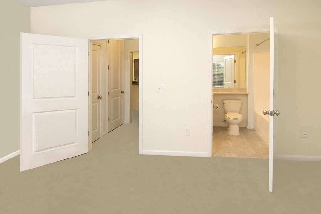 a bedroom and a bathroom with a toilet and a open door