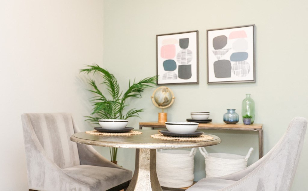 a dining room with two chairs and a table and two pictures on the wall