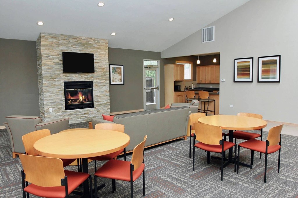 A stone fireplace is in the corner of a room with a table and chairs.