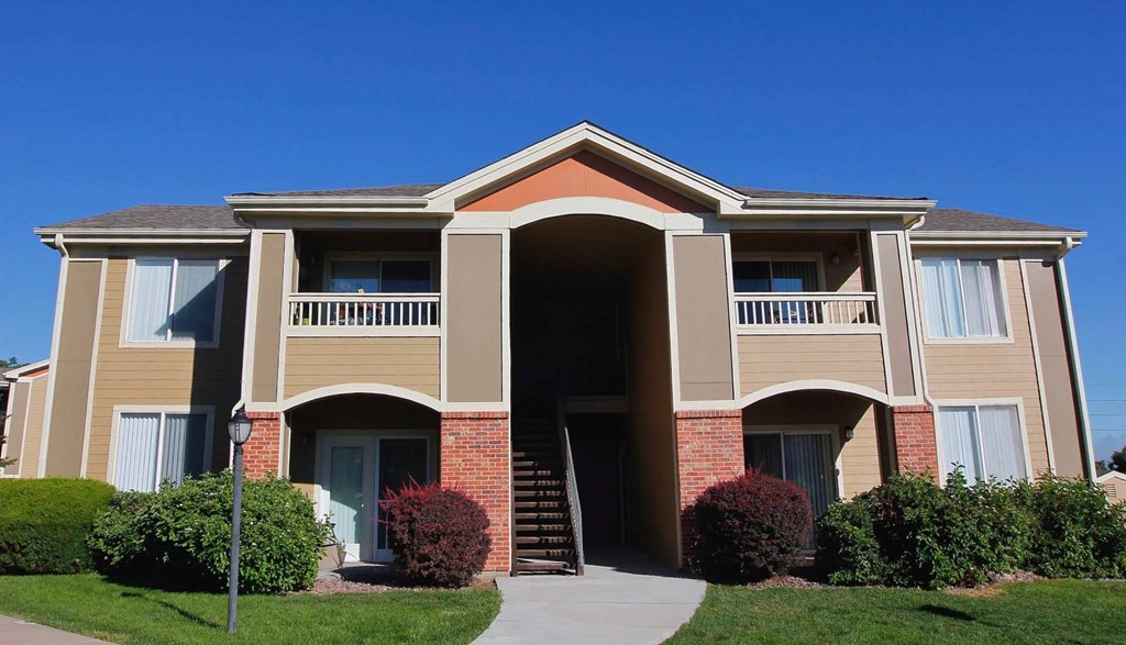 A large, beige apartment building with a red brick entrance.