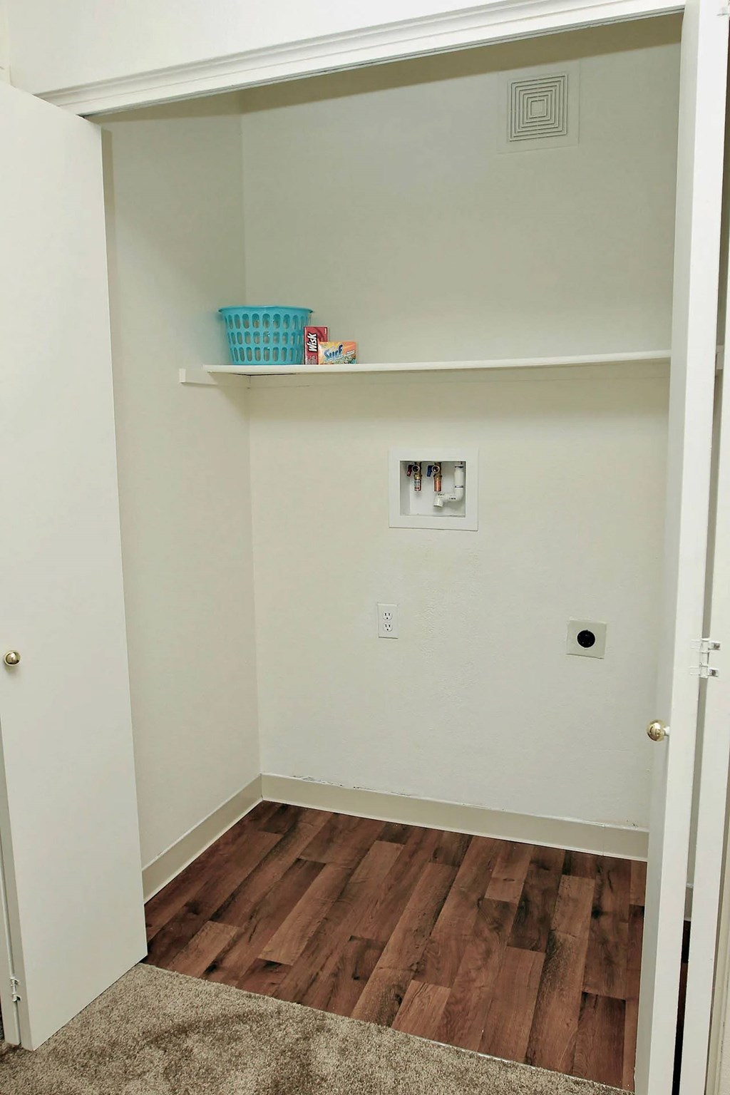 A small white closet with a basket on the shelf.