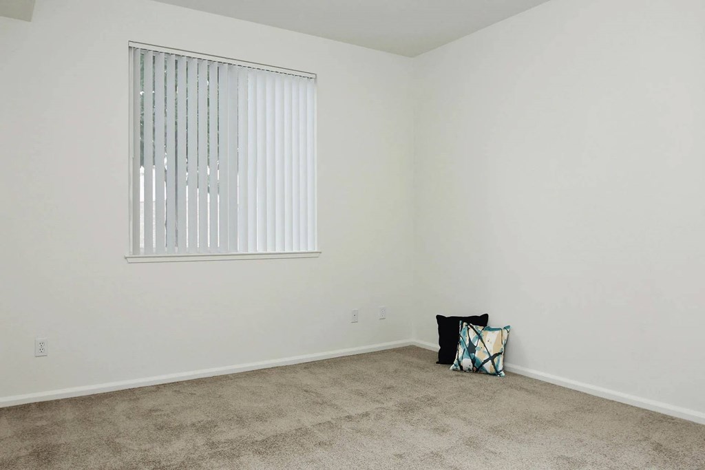 A room with a window and a pillow on the floor.