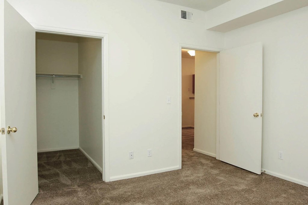 A room with carpeted flooring and two open doors.