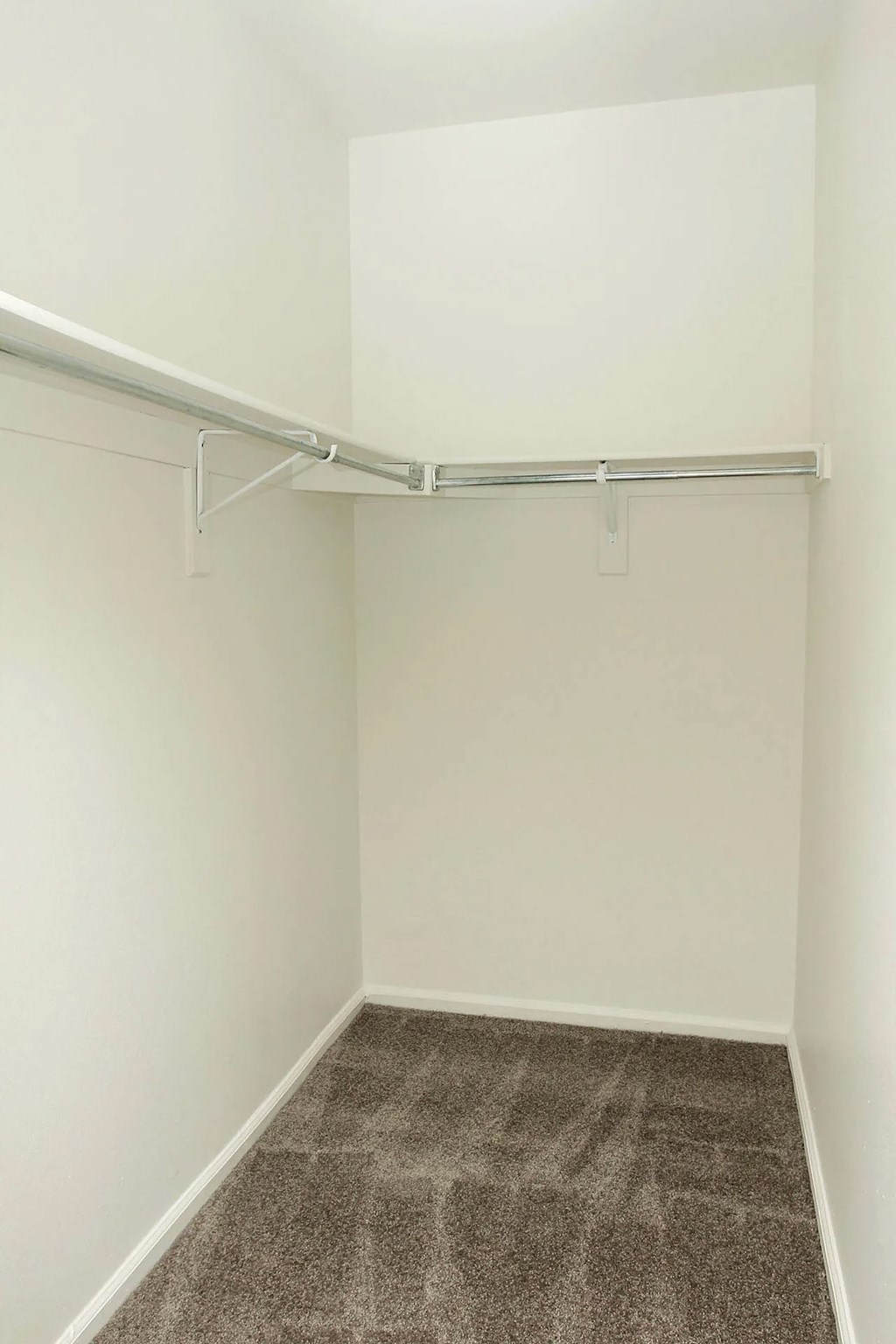 A white closet with a carpeted floor and a white door.