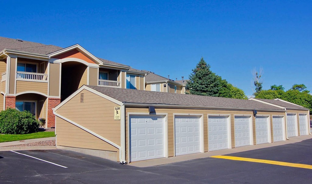 A row of garages in front of apartment buildings.