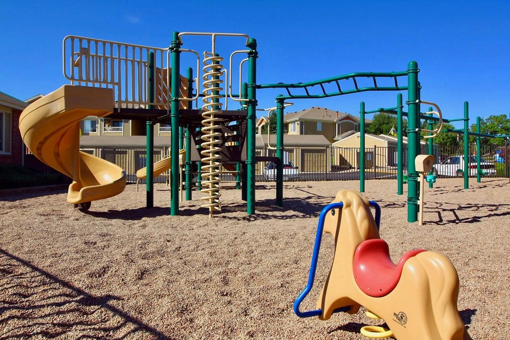 A playground with a yellow slide and a green monkey bar.