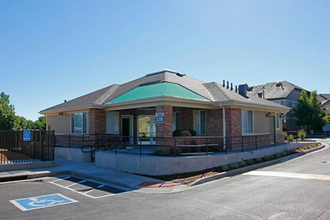 A small building with a green roof is located on a street corner.