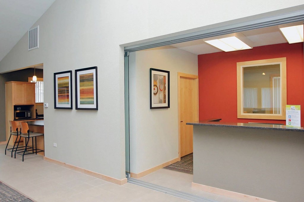 A hallway with a red wall and two framed pictures on the wall.