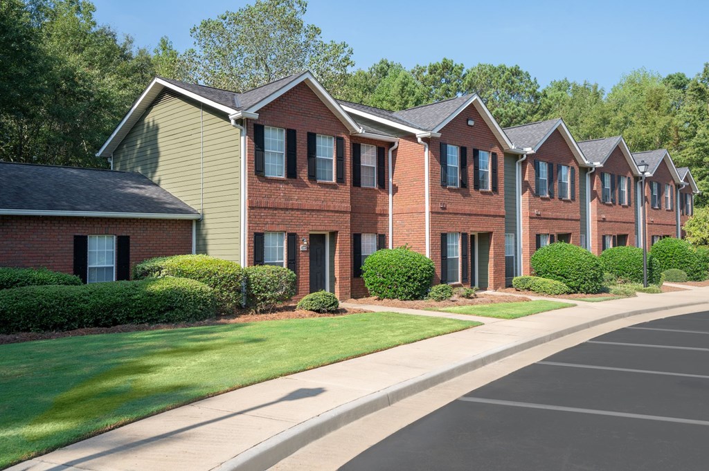 A row of red brick houses with green lawns in front.