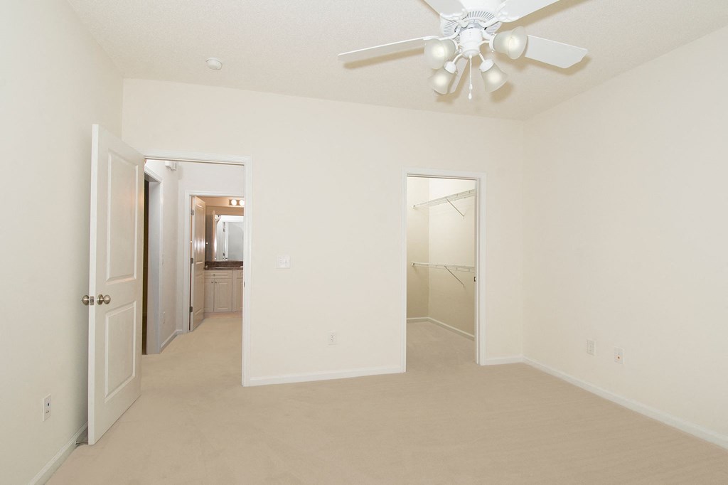 an empty living room with a ceiling fan and a closet