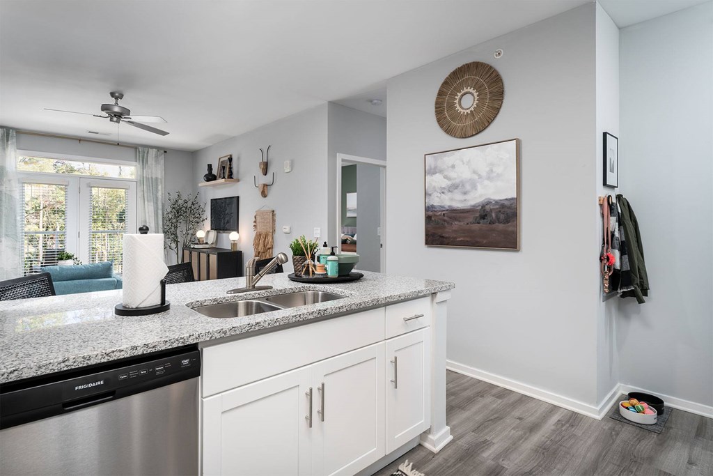 A kitchen with a stainless steel dishwasher and white cabinets.