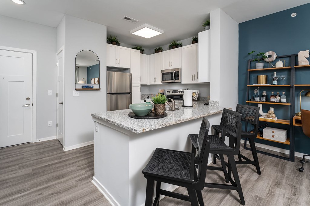 A kitchen with white cabinets and a white island with a counter top.
