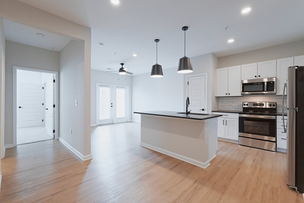A modern kitchen with a black countertop and stainless steel appliances.