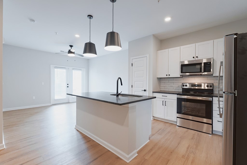 A modern kitchen with a black countertop and stainless steel appliances.