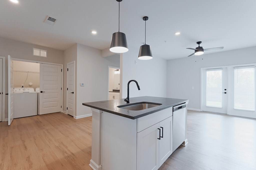A modern kitchen with a large island and pendant lights.