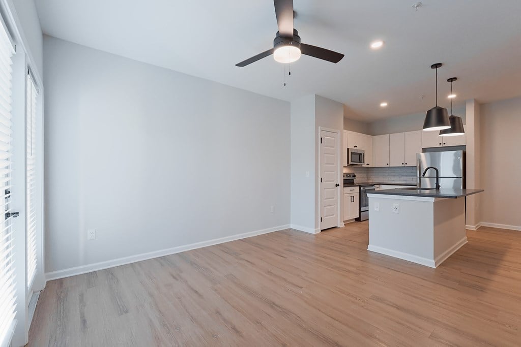 A modern kitchen with a ceiling fan and wooden flooring.