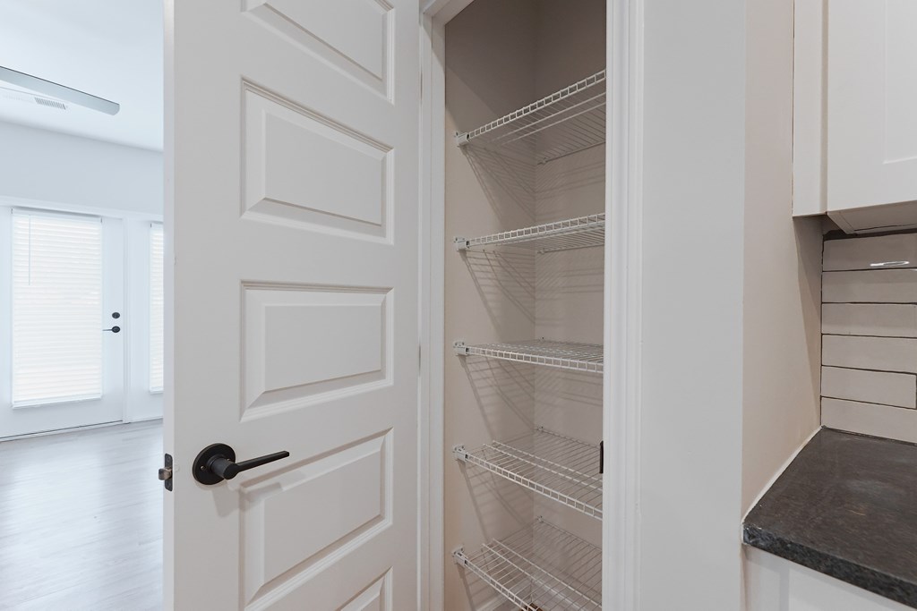 A white door is open to reveal a set of empty white shelves.