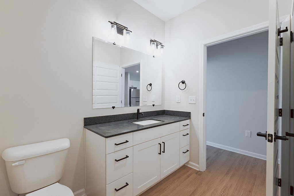 A bathroom with a toilet, sink, and mirror.