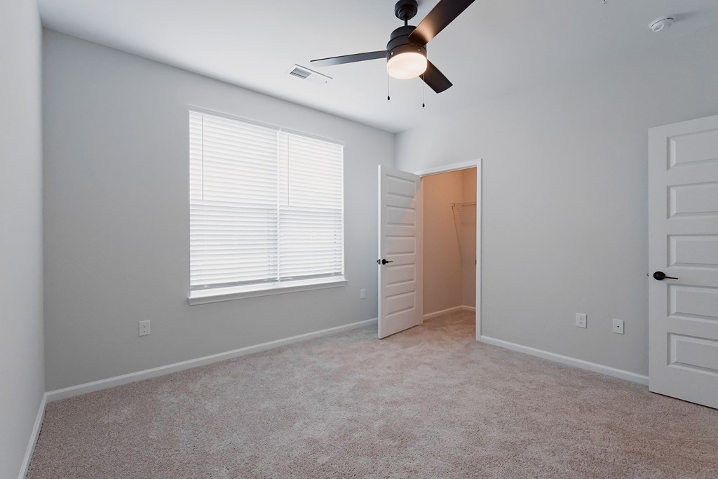 A room with a ceiling fan and a door.