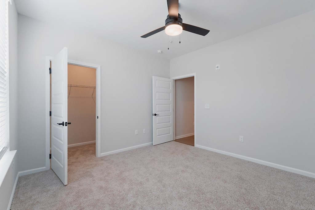 A room with a ceiling fan and two doors.